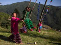 A woman helps a kid to ride a traditional swing set up as part Dashain festival at Sankhu, Nepal on Wednesday, October 13, 2021. (