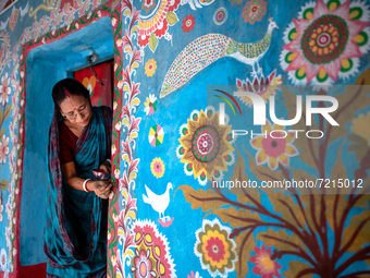 A woman draws traditional motifs on a wall of her house at Tikoil village in Nachole upazila of Chapainawabganj district of Bangladesh. (