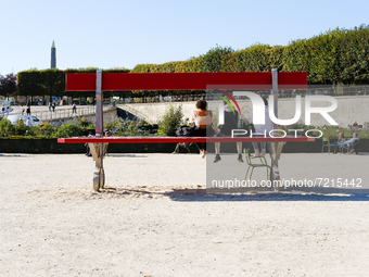 Three girls seated on the Double-bench, a work by Lilian Bourgeat in the Tuileries garden for the FIAC 2021.(
