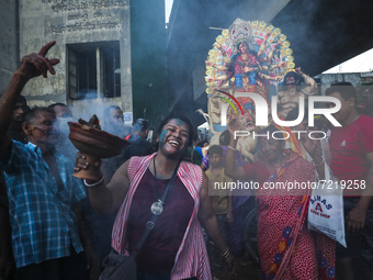 Hindu devotees dance in front of an idol of the Hindu Goddess Durga before immersing in the Buriganga River on the final day of the Durga Pu...