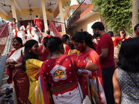 Hindu women devotees apply 'sindhur', or vermillion powder, on each other after worshipping the idol of the Hindu goddess Durga, on the last...