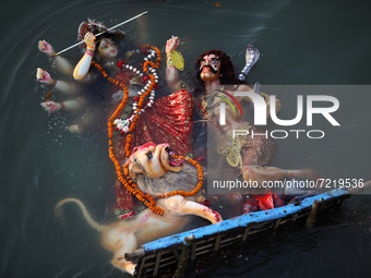 Hindu devotees immerse a clay idol of the Hindu Goddess Durga in the Buriganga River on the final day of the Durga Puja festival in Dhaka on...