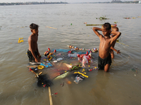 Ragpickers collects Hindu goddess structures after into Ganges River by Hindu devotees during immersion of Durga idols, in Kolkata, India, O...