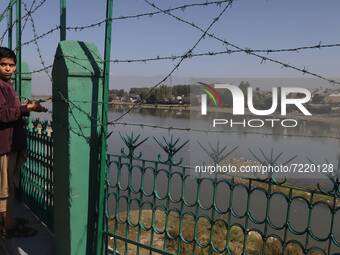 A Kashmiri Muslim Boy holds the Barbed Fencing Wire inside the premises of Jama Masjid as he Looks towards River Jehlum in Sopore, District...