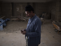 Abdolghani Jamshidi-60, An Afghan refugee who works as a construction worker, uses his mobile phone as he rests while working in a residenti...