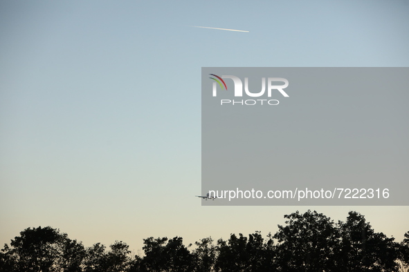 A plane flyes above the trees during the evening hours in Stuttgart, Germany on October 9, 2021 