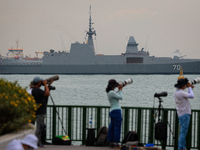 People take pictures of a flypast as the Singapore's RSS Steadfast naval vessel is seen displayed at Marina South on October 18, 2021 in Sin...