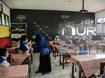 Students attend a lesson in a classroom at a primary school during its reopening as a small number of Bogor's students head back to their sc...