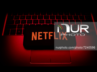 Netflix logo displayed on a phone screen and a laptop keyboard are seen in this illustration photo taken in Krakow, Poland on October 18, 20...
