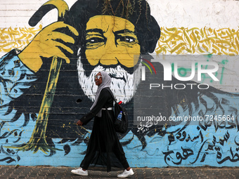 A Palestinian youth woman walks past a mural painting in Gaza City on October 20, 2021.
 (