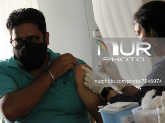 A health worker inoculates a man during a vaccination drive against coronavirus inside a school in New Delhi, India on October 20, 2021. Ind...