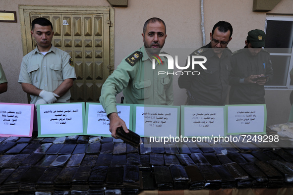 Hamas security forces guard a display of bars of hashish, kilos of Marijuana and thousands of pills of Tramadol, that they say have been sei...