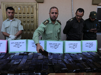 Hamas security forces guard a display of bars of hashish, kilos of Marijuana and thousands of pills of Tramadol, that they say have been sei...