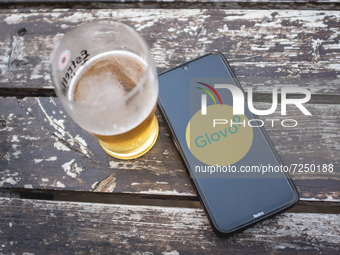In this photo illustration a Glovo logo is display on a smartphone screen and a glass of beer in Sintra, Portugal on October 21, 2021. (