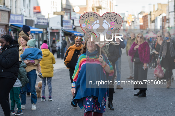 LONDON, UNITED KINGDOM - OCTOBER 22, 2021: A local resident holds a placard as Little Amal, a 3.5 metre-tall giant puppet representing a nin...
