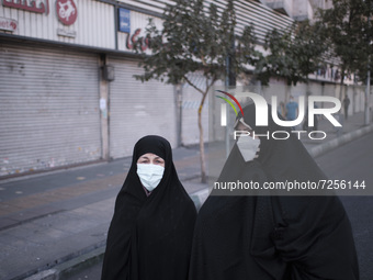 Iranian veiled women wearing protective face masks walk along an avenue to the University of Tehran for taking part the Friday prayers cerem...