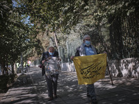 An Iranian elderly man wearing a protective face mask carrying an anti-U.S. flag while walking along an avenue to the University of Tehran f...