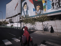 An Iranian woman wearing a protective face mask walks under a portrait of Iran’s Supreme Leader Ayatollah Ali Khamenei near the University o...