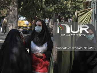 A female member of the Iranian Red Crescent (C) wearing a protective face mask checks body temperature of a veiled woman at an entrance of t...