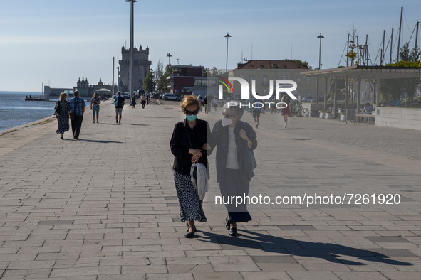 Two women wearing protective masks walk near the Belem Tower in Lisbon. 20 October 2021. Most regions in mainland Portugal show an 