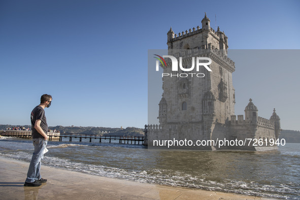 A person wearing a protective mask stands near the Torre de Belem tourist area in Lisbon. 20 October 2021.  Most regions in mainland Portuga...