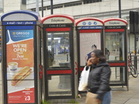 Payphones standing idle as a person walks by speaking on their mobile phone on Tuesday 5th May 2015. (