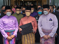 Malaysia's Finance Minister Tengku Zafrul Tengku Abdul Aziz (C) holds a briefcase containing the 2022 budget speech outside the Finance Mini...