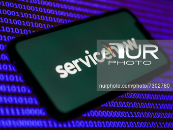 ServiceNow logo displayed on a phone screen and binary code displayed on a laptop screen are seen in this illustration photo taken in Krakow...