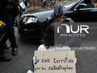 A riot policeman tries to convince a XR activist to quit the road as she blocks it. Her placard reads 'I'm terrified by disaster more numero...