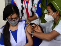 A Bangladeshi school student receives a first dose of the Pfizer COVID-19 vaccine at the Ideal School and College center in the Motijheel ar...