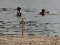 People swim in Verbne lake in Kiev next to the caution “Swimming is temporarily prohibited” board. Several people were deadly infected with...