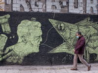 A man is passing front of a graffiti at the enter of a shop in the center of Athens, Greece on November 10, 2021. Mandatory negative Coronav...