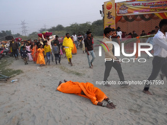 A Hindu devotee offers prayer while laying on the ground as they arrive to worship the Sun god on the banks of Yamuna river, on the occasion...