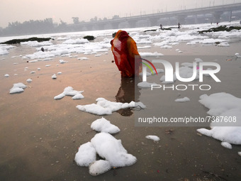 A Hindu devotee performs rituals as she stands amidst the polluted waters of the river Yamuna covered with a layer of foam, on the occasion...