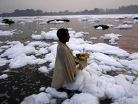 A Hindu devotee performs rituals as he stands amidst the polluted waters of the river Yamuna covered with a layer of foam, on the occasion o...
