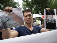 A resident displays the pictures of his damaged home during the protest. - Hundreds of residents from near the chemical explosion zone of Ti...