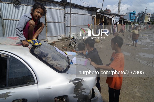 August 17, 2015, Kathmandu, Nepal --  Children put their books to dry in the sun as other cleans floodwater from his house in the slum area...