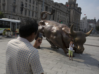 Visitors take pictures at the replice of the Bull of Wall street at the Bund, Shanghai, Aug. 17 2015. (