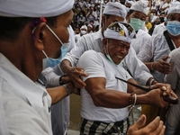 Balinese Hindu man attempts to stab himself with traditional Keris dagger while in trance during the sacred ritual of Ngerebong amid COVID-1...