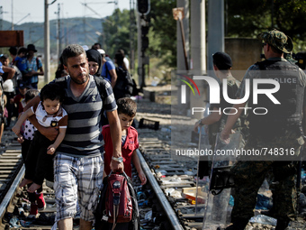 A man crosses the Greek-Macedonian border with his children. Gevgelija, August 23, 2015. (Photo by Kostis Ntantamis/NurPhoto)