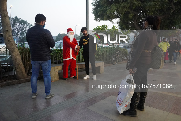 People click pictures with a man dressed as Santa Claus at a marketplace on the eve of Christmas, amidst the coronavirus (COVID-19) pandemic...