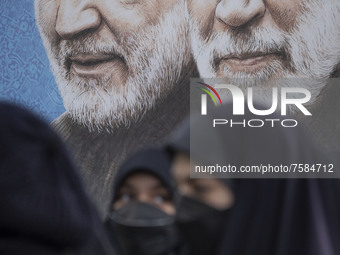 Iranian veiled women carrying Iran flags as they walk past a portrait of the Iranian top IRGC commander, General Qasem Soleimani (L) and Ira...
