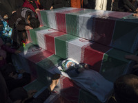 A baby is pictured on coffins containing remaining bodies of Iranian warriors who have been killed during the Iran-Iraq war, while taking pa...