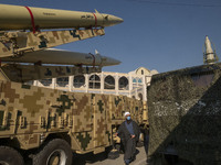 An Iranian cleric walks past Iranian solid-propelled road-mobile single-stage missile, Zolfaghar Basir (Top), and Dezful medium-range ballis...
