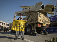 An Iranian elderly man holds an anti-U.S. flag while standing under the Iranian solid-propelled road-mobile single-stage missile, Zolfaghar...