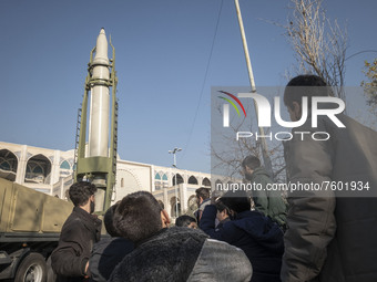 Iranian schoolboys stand next to the Iranian Qiam short-range surface-to-surface ballistic missile while visiting a military exhibition to m...