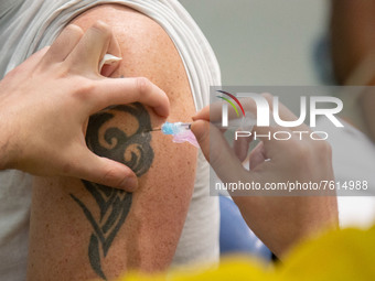 Closeup at the arm with a tatoo during the vaccination of a man. Vaccination center in Eindhoven with 20 lanes and the capacity of 7500 vacc...