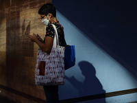 A woman wearing protective mask uses her mobile phone while waiting for a bus on January 13, 2022 in Singapore. 
 (