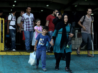 Families of Syrian refugees and migrants from Asia disembark in the port of Piraeus, near Athens, on September 5, 2015.  The chartered by th...