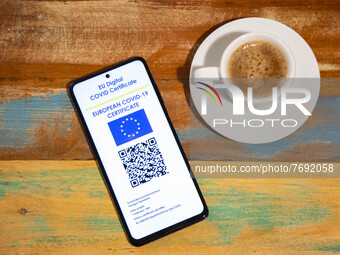 Photo illustration of a display of a mobile phone with a European EU digital Covid-19 vaccination certificate with a QR, an international va...